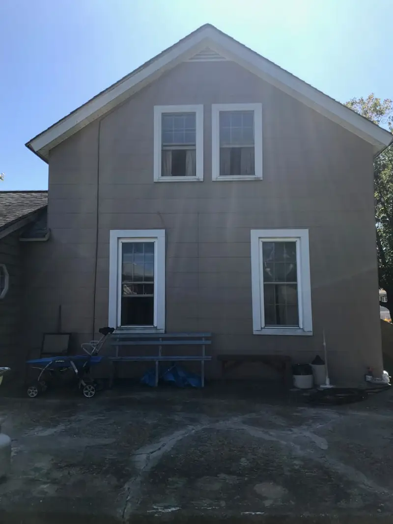Back of a two-story shingled house with a paved yard, Lindenhurst, NY