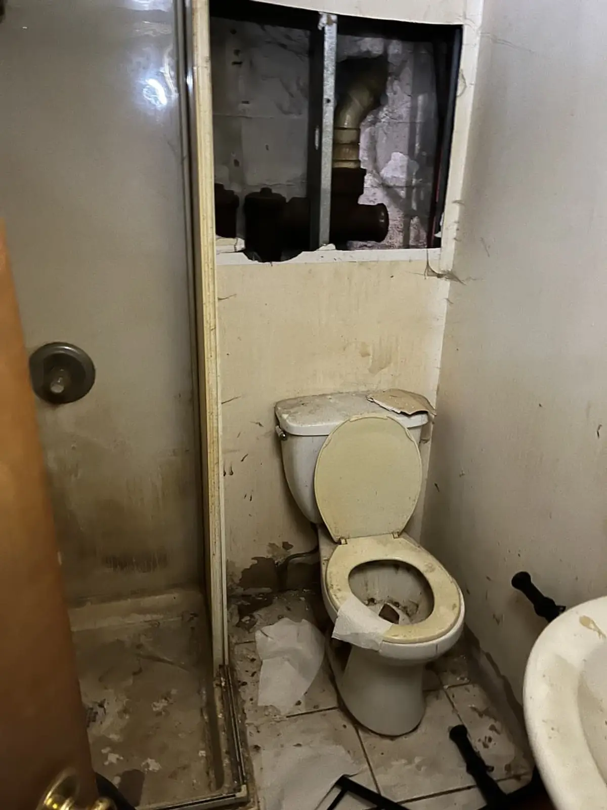 Selling a house as-is in Lindenhurst: bathroom with a hole broken through the wall above the toilet