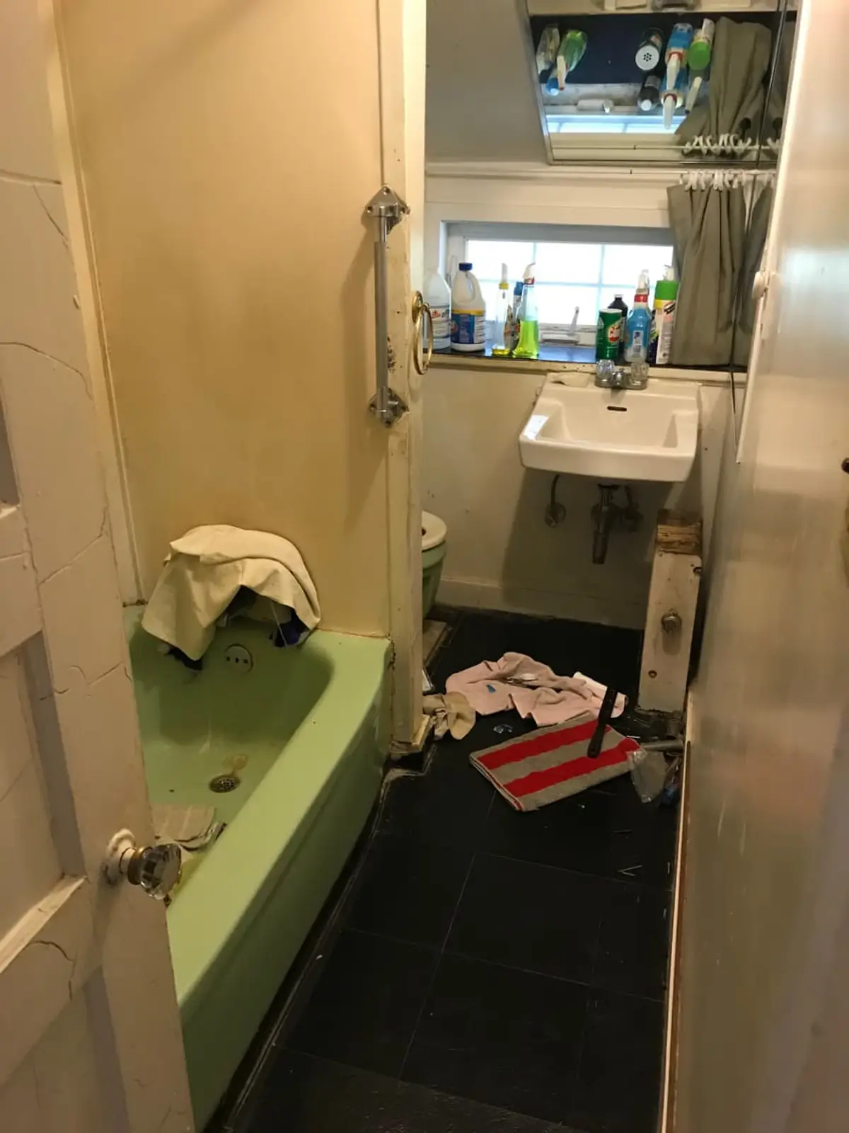 Selling a house with a reverse mortgage in Lindenhurst: dated bathroom with a green tub and dark tile floor