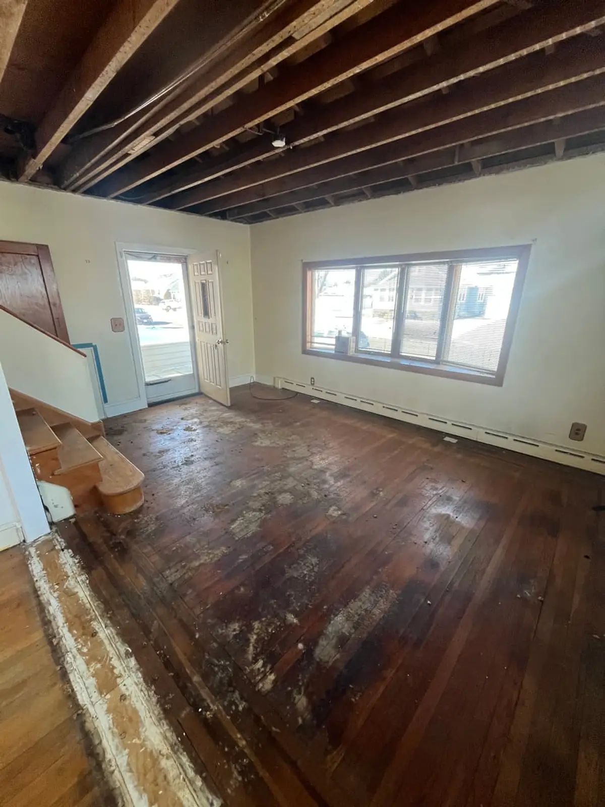 Selling a fire-damaged house in Lindenhurst: living room with the ceiling opened to the joists during renovation