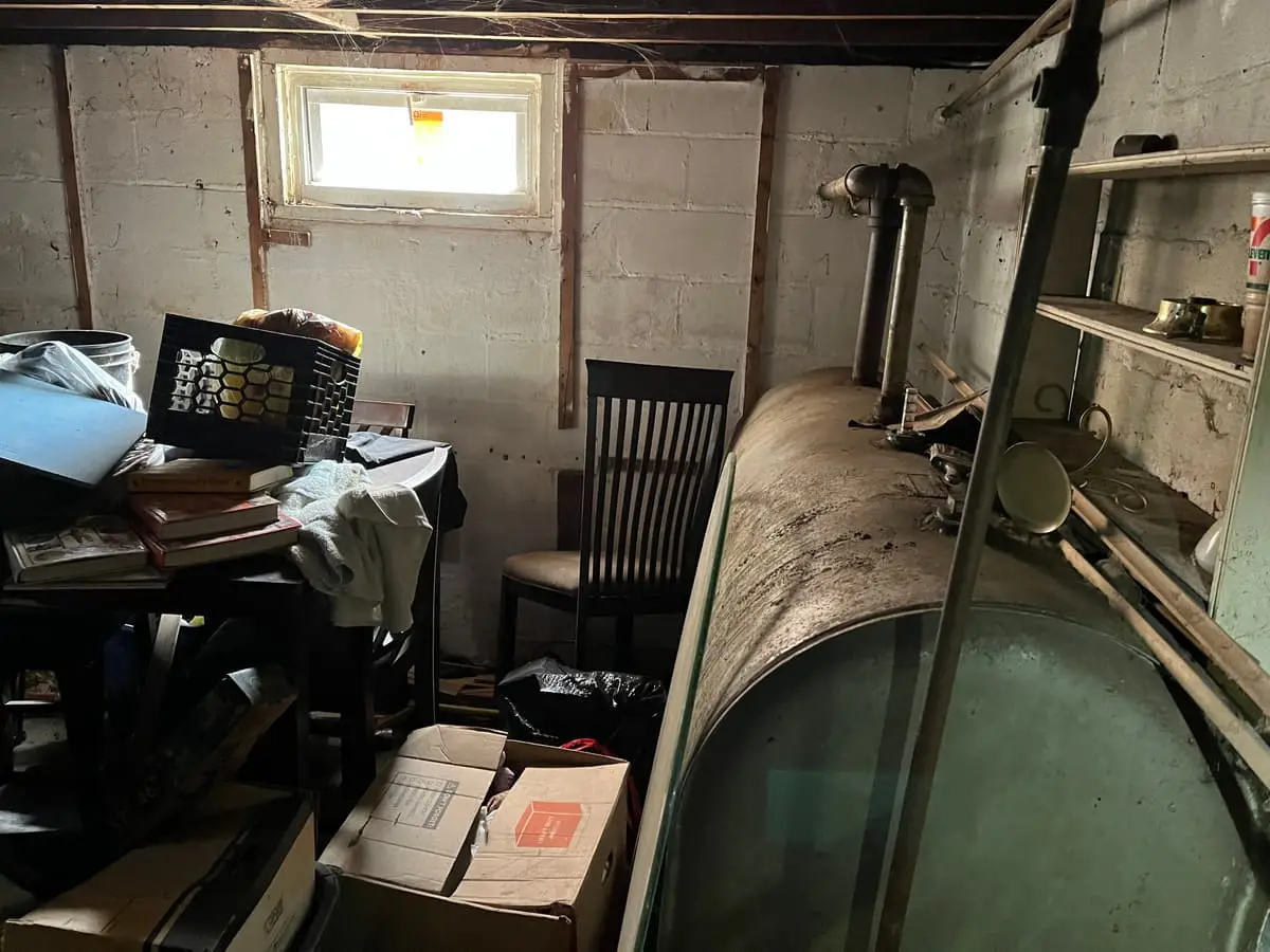 Selling a house with an oil tank in Lindenhurst: old oil tank in a cluttered unfinished basement