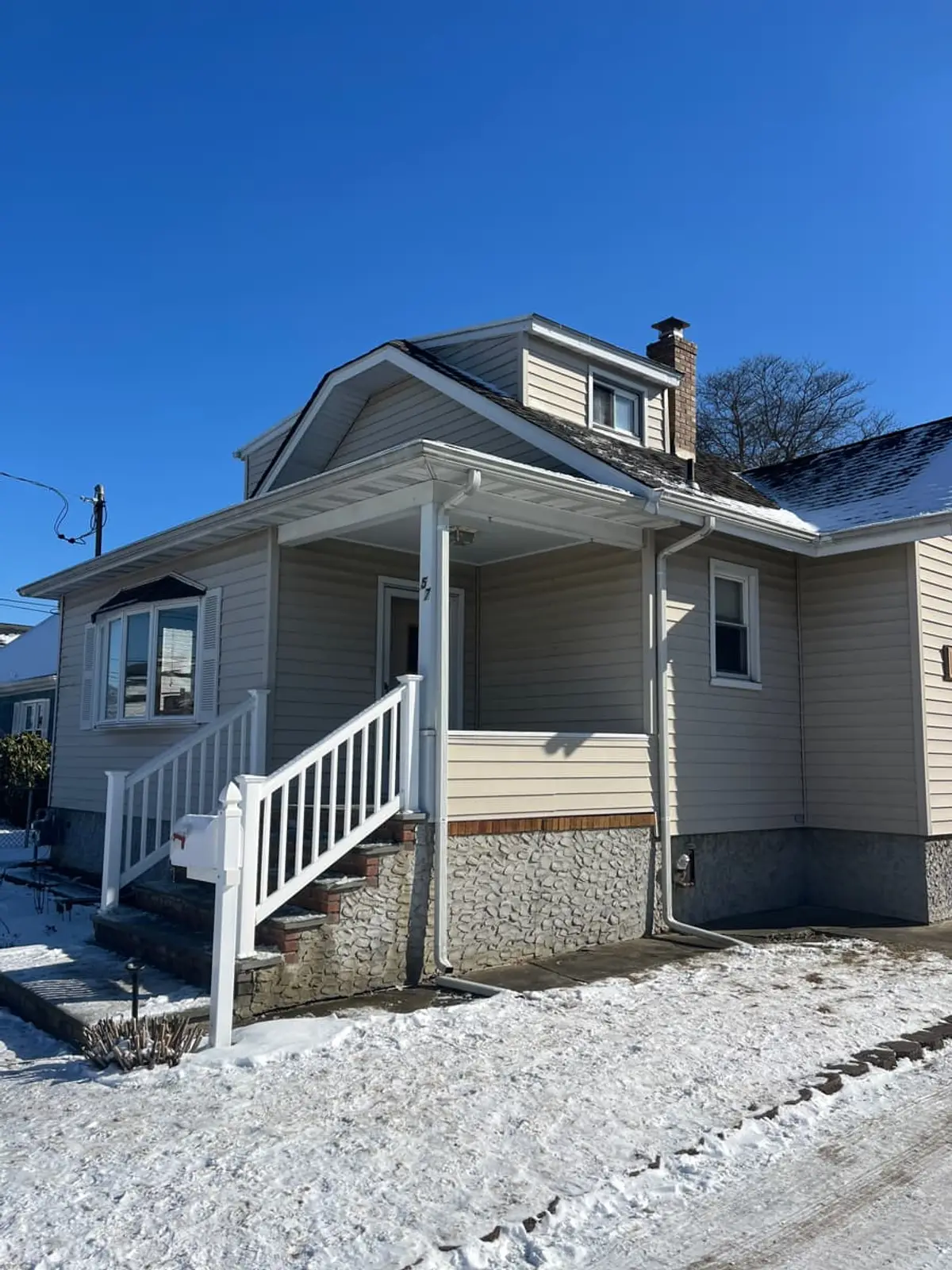 Selling a rental property in Lindenhurst: raised Cape with a front porch and new white stair rails