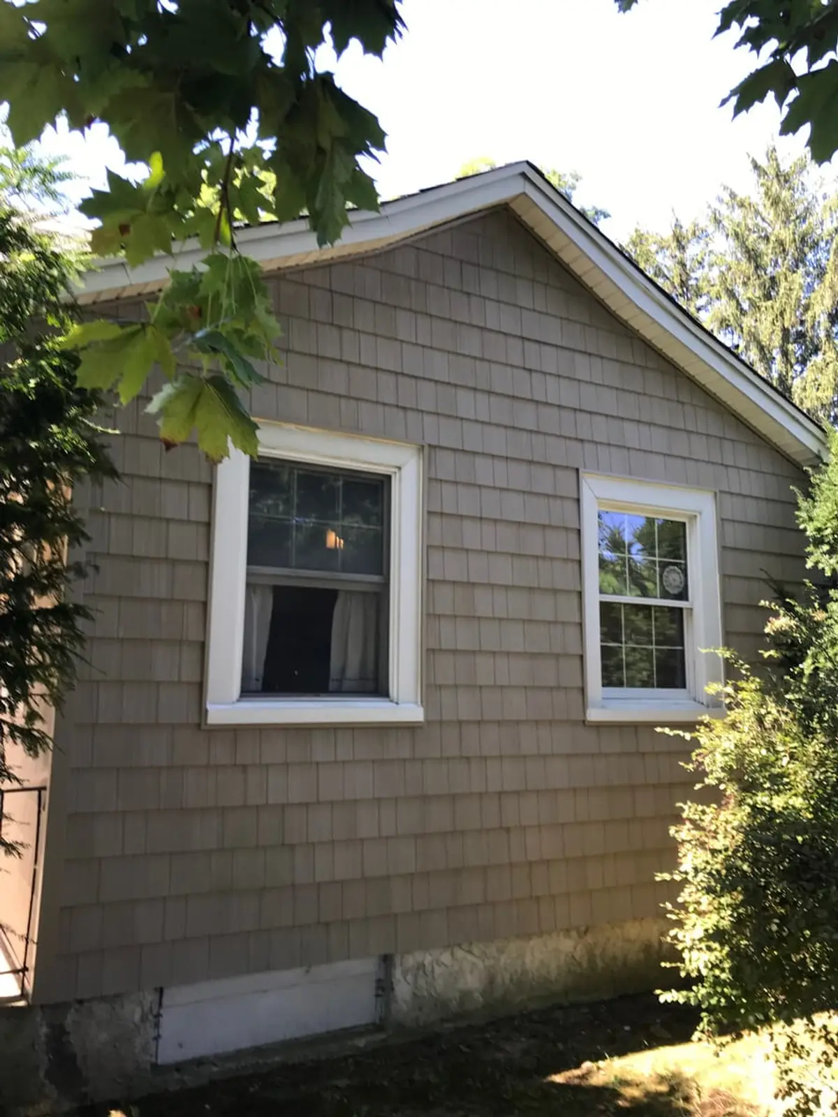 Selling a multi-family house in Lindenhurst: side of a shingled cottage with white-trimmed windows