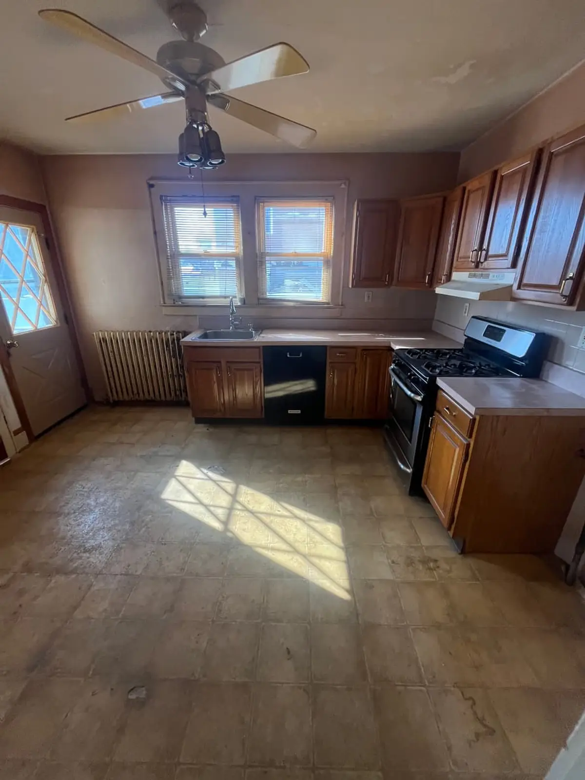 Selling a house with multiple heirs in Lindenhurst: vacant dated kitchen with wood cabinets and a worn vinyl floor